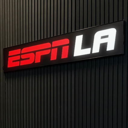 Front lit ESPN LA channel letter sign glowing on a dark wall